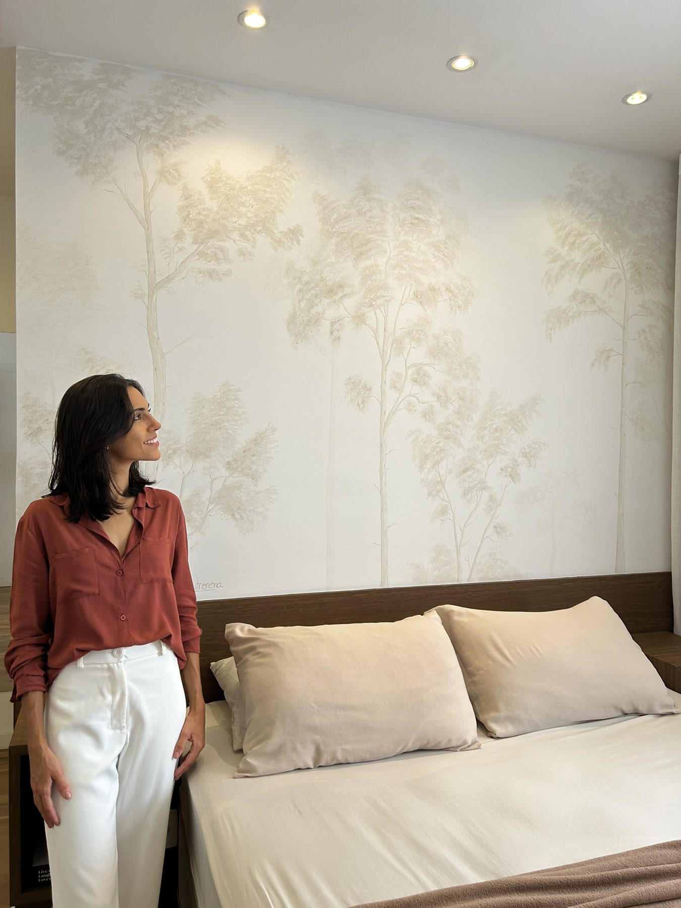 Árvores em tons claros pintadas na parede de um quarto.