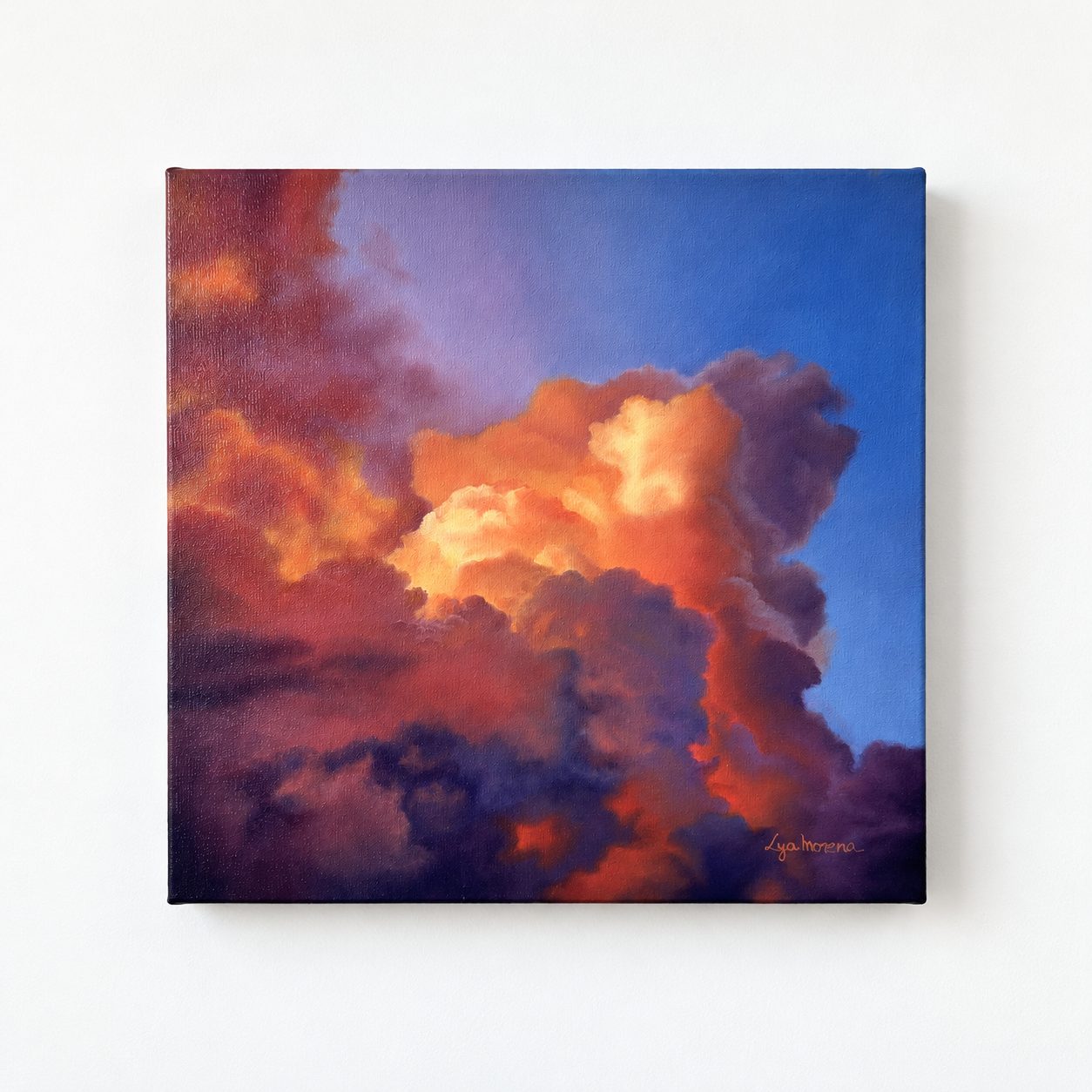 Nuvens iluminadas em laranja e amarelo, com sombras violetas, diante de um céu azul ao entardecer.